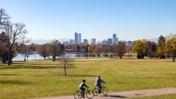 Two bike riders on trail in part with Denver, Colorado skyline in background