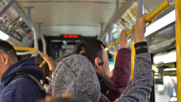 Bus riders standing on crowded city bus, holding top rail