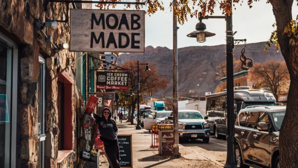 Person standing under sign that says "Moab Made" in downtown Moab, Utah.