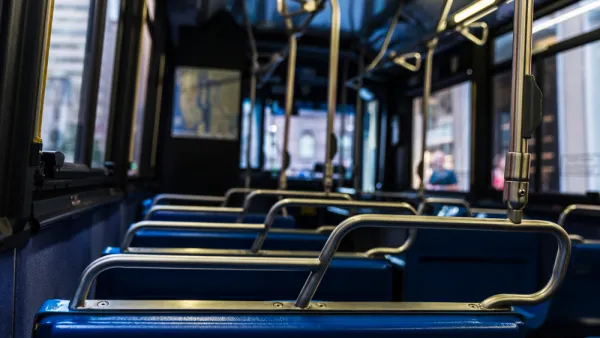 Close-up view of empty bus from behind seat. Seats have blue upholstery