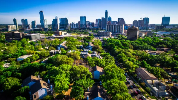 Aerial view of green trees over residential neighborhood with Austin, Texas skyline in the background