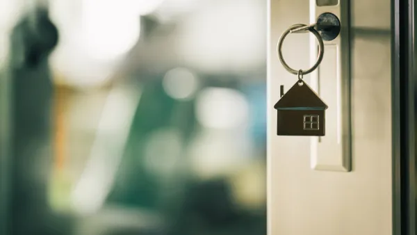 Close-up of key in door lock with house-shaped keychain hanging from it