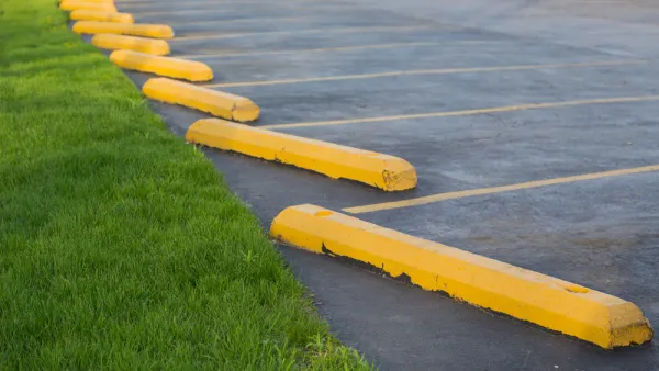 Parking lot with yellow concrete bars adjacent to green grass