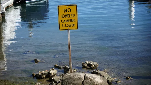 Yellow "no homeless camping" sign in water at California beach