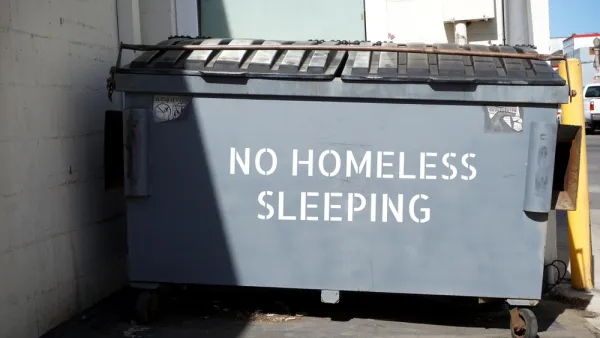"No homeless sleeping" stenciled on grey dumpster in urban alley
