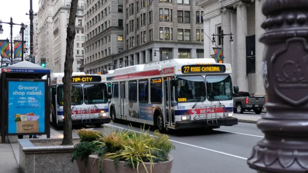 Two white SEPTA buses with red and blue lines on urban Philadelphia street