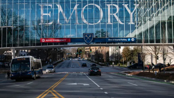 View of enclosed glass pedestrian bridge over street with EMORY in large letters across the glass