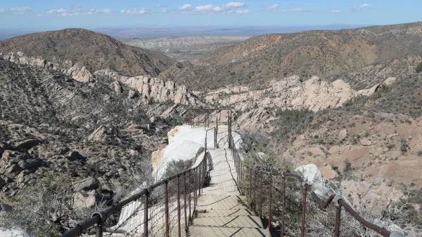 View of hiking trail descending into desert mountains with steps carved into stone and guardrails at Devil's Punchbowl Natural Area, Los Angeles County