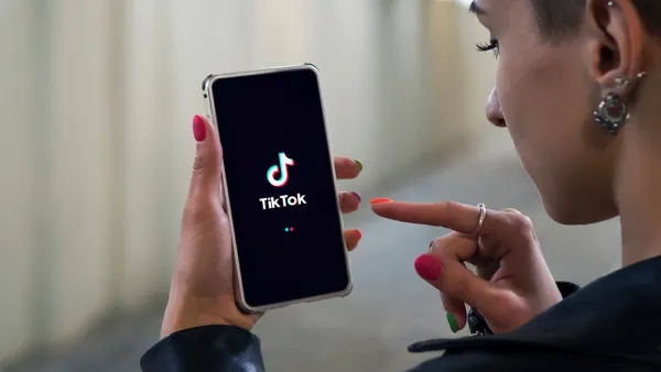 Woman holding phone with TikTok logo