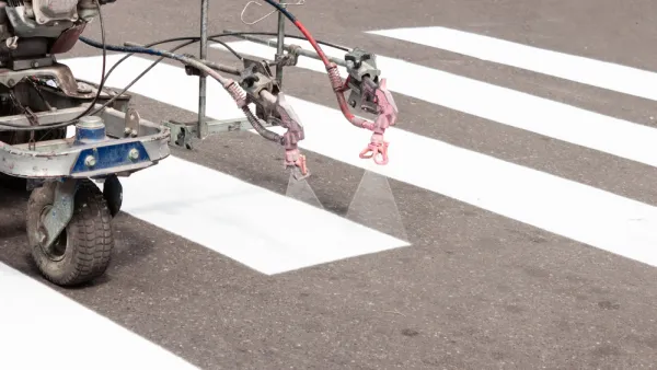 Machine spraying white crosswalk lines on street