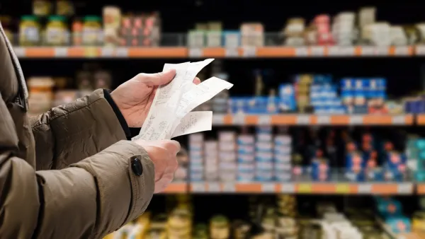 Close-up of person holding receipt with grocery store shelves in background
