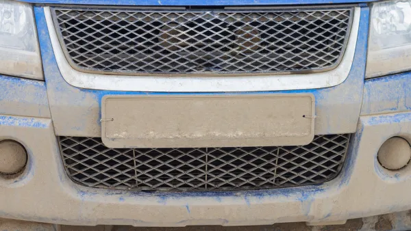 Close-up of license plate on blue car covered in mud, license plate is unreadable.