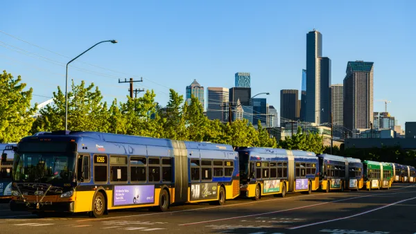 Seattle buses in line at a depot with Seattle skyline in background