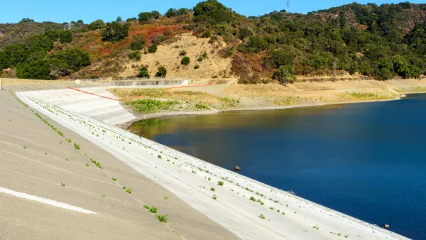 Concrete dam of almost dried, low water level Stevens Creek reservoir in San Francisco Bay Area, California.