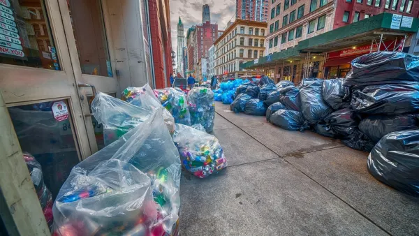 Black and blue bags of trash piled on a New York City sidewalk