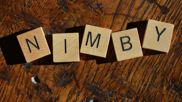 NIMBY spelled out in Scrabble tiles on a wood table