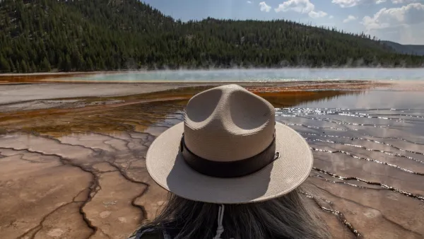 View of park ranger with tan hat from behind, ranger looking out at Grand Prismatic Spring in Yellowstone National Park, Wyoming
