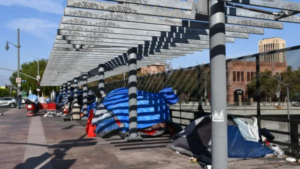 A group of tents inhabited by unhoused people line a freeway overpass in Los Angeles, California