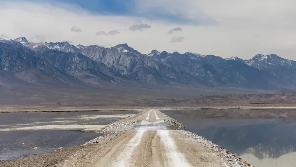 Unpaved road through Owens Lake bed with Sierra Nevada mountains in the background
