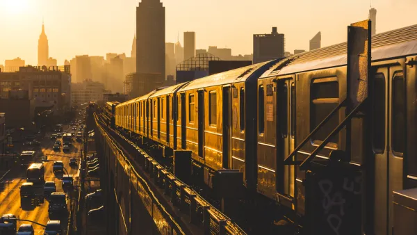 Golden sunset view of New York City subway train on elevated track with Empire State Building in background