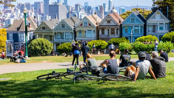 People lounging on grass in Alamo Square park in San Francisco overlooking painted ladies Victorian houses and city skyline