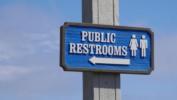 Blue "Public Restrooms" sign with arrow against a blue sky