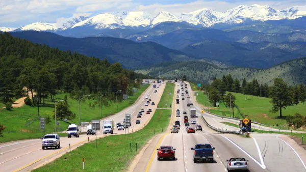 Cars on highway in Colorado with snow-capped mountains in background