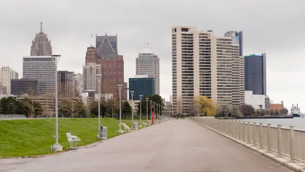 Waterfront walkway with benches and Detroit skyline in the background