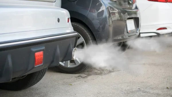 Close-up of back of three cars in a line with smoke coming from tailpipes