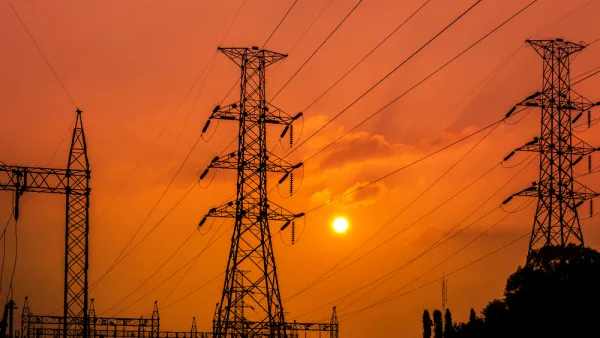Power lines and towers at a substation against a red sunset backdrop