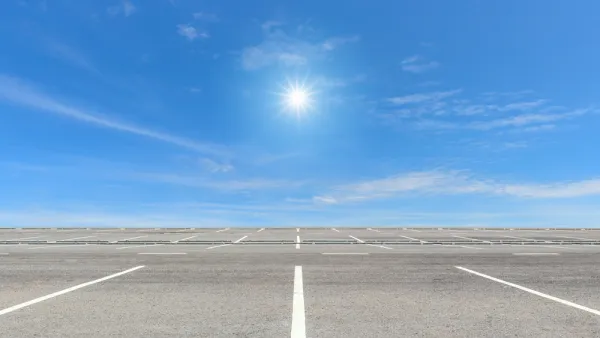 Vast, empty parking lot with blue sky and bright sun in background