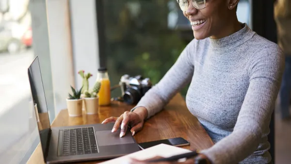 Woman sitting at countertop with laptop facing window