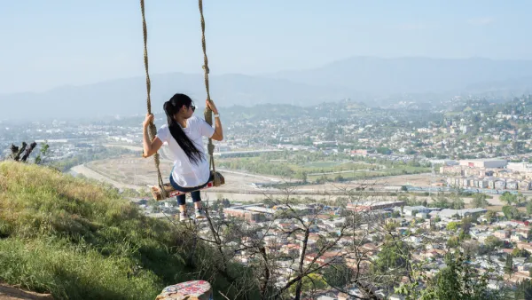 Girl swinging on rope swing overlooking Los Angeles
