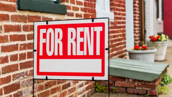 Red and white For Rent sign in front of brick building with flowerpots in background