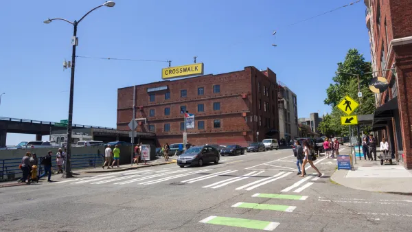 Pedestrians in zebra crosswalk with green bike lane in downtown Seattle, Washington with three-story brick building in background