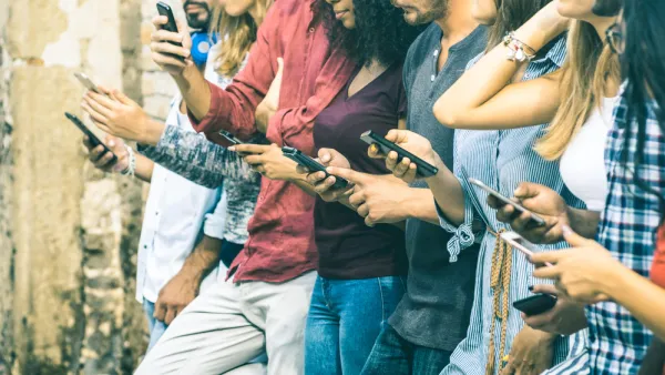 A row of young people outdoors using smartphones