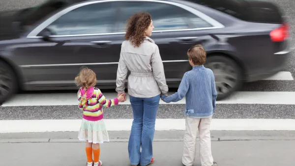 Mother and two young children waiting to cross street at busy crosswalk