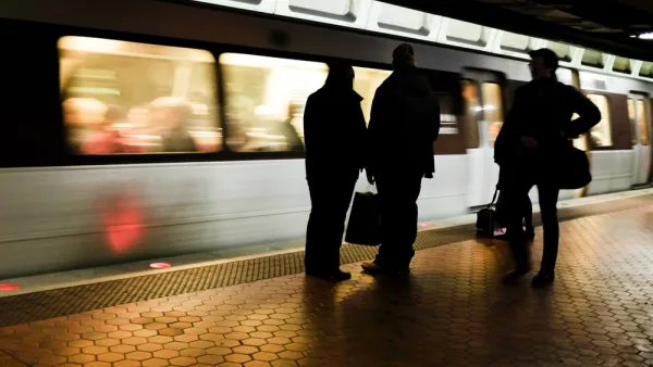 Three commuters on train platform sillhouetted against moving train