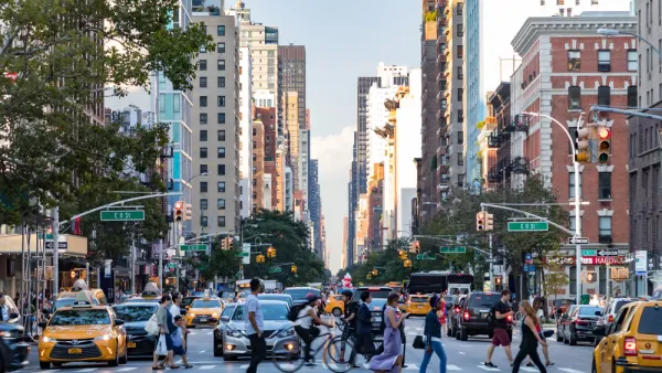 Pedestrians crossing a busy crosswalk on New York City street with tall buildings in background