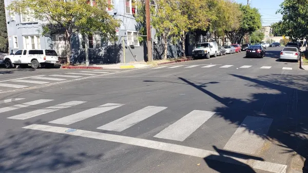 A white crosswalk painted by Crosswalk Collective LA in Los Angeles, California.